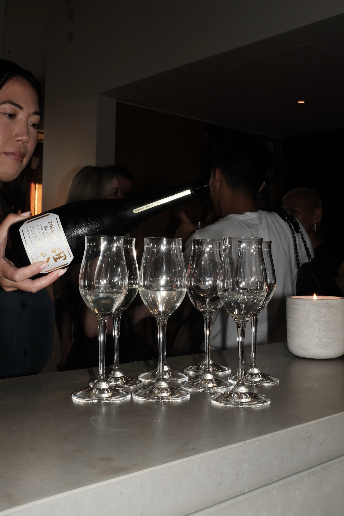 A bottle held beside a row of empty glasses