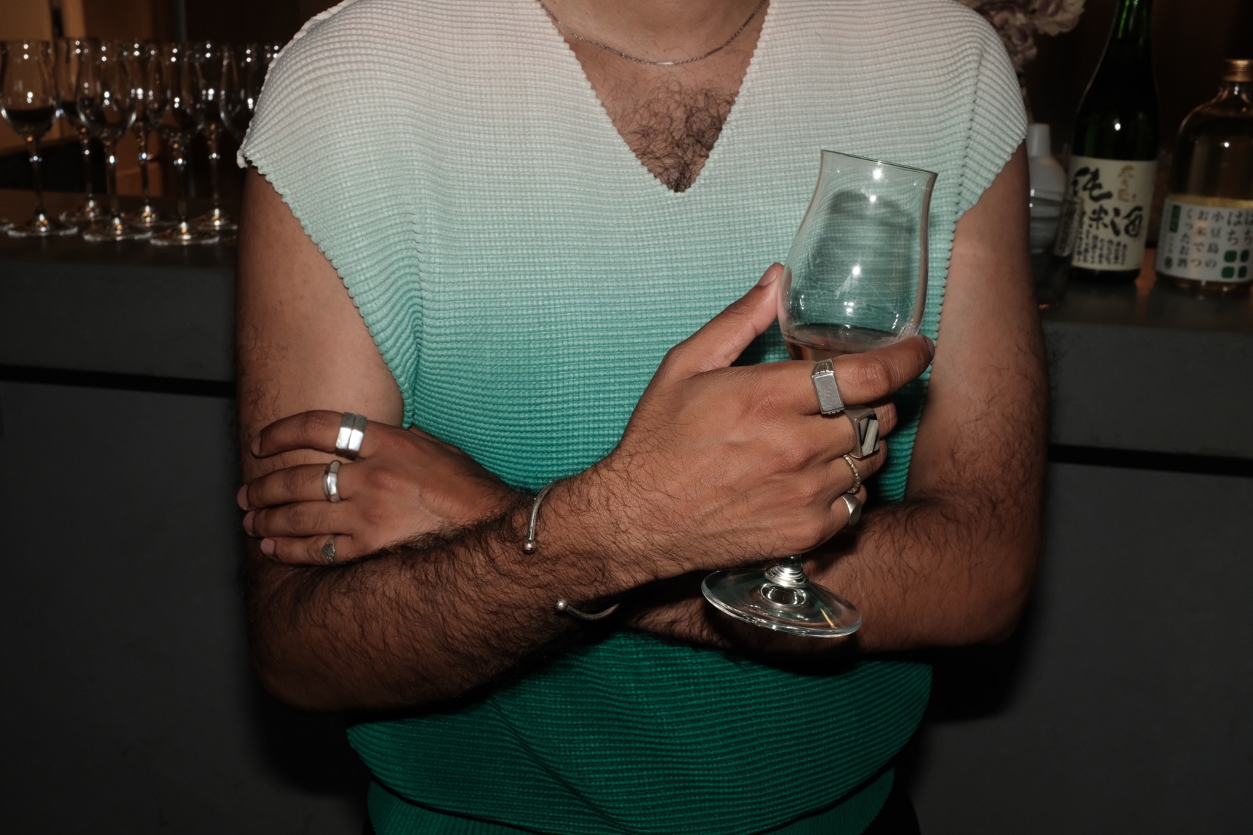 A guest with a glass, bottles behind